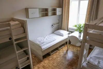 a small room with a bed and a desk and a bed at C - Punkt Hostel in Ljubljana