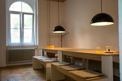 a room with a table and two lights and benches at C - Punkt Hostel in Ljubljana
