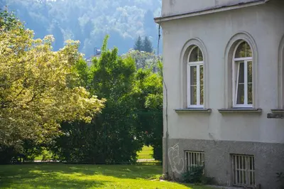 a building with two windows and a yard with trees at C - Punkt Hostel in Ljubljana