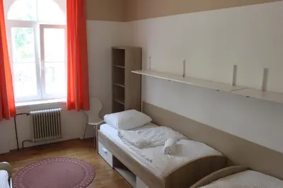 a small room with two beds and a window at C - Punkt Hostel in Ljubljana