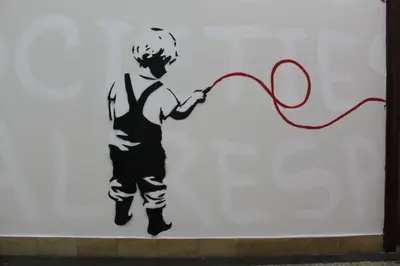 a wall art of a boy with a red string at C - Punkt Hostel in Ljubljana