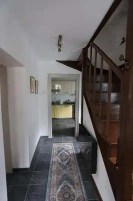 a hallway with a staircase and a rug at Hiša Nad Reko Baca in Most na Soči