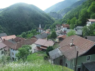a small town in a valley with mountains in the background at Hiša Nad Reko Baca in Most na Soči