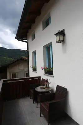 a patio with a table and chairs on a balcony at Hiša Nad Reko Baca in Most na Soči