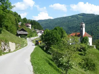 a winding road in a village with a clock tower at Hiša Nad Reko Baca in Most na Soči