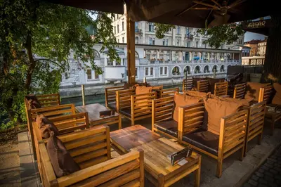 a group of wooden chairs and tables and an umbrella at Cacao Rooms in Ljubljana