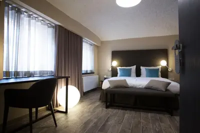 a bedroom with a bed with blue pillows and a desk at Cacao Rooms in Ljubljana