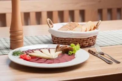 a plate of meat and bread and a basket of bread at Gostilna in picerija Harlekin in Ribnica