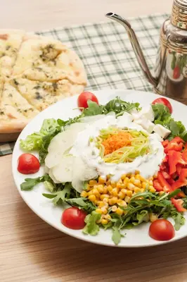 a white plate of food with vegetables on a table at Gostilna in picerija Harlekin in Ribnica
