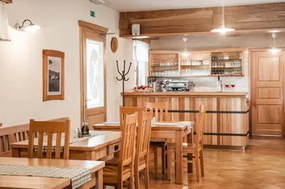 a dining room with a table and chairs and a kitchen at Gostilna in picerija Harlekin in Ribnica
