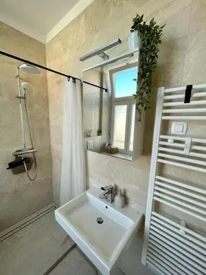 a bathroom with a sink and a shower and a mirror at Mirno in elegantno stanovanje - Parkirišče, Netflix, wifi in Maribor