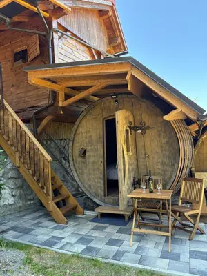 an outside view of a large wooden building with a table at Glamping Medvedjek - Nočitev v vinskem sodu in Velika Loka