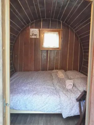 a bed in a small room with a window at Glamping Medvedjek - Nočitev v vinskem sodu in Velika Loka