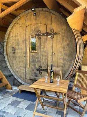 a wooden table with two wine glasses in front of a barrel at Glamping Medvedjek - Nočitev v vinskem sodu in Velika Loka