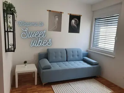 a living room with a blue couch in a room at Sweet Vibes Studio at Šiška district, with Parking in Ljubljana