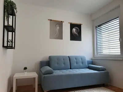 a blue couch in a living room with a window at Sweet Vibes Studio at Šiška district, with Parking in Ljubljana