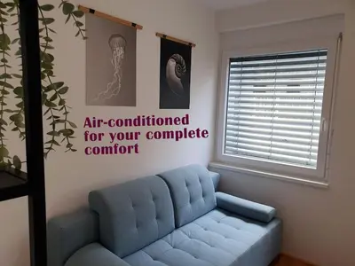 a blue couch in a living room with a window at Sweet Vibes Studio at Šiška district, with Parking in Ljubljana