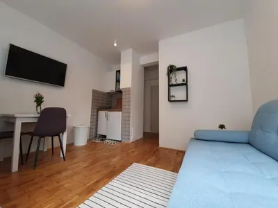 a living room with a blue couch and a table at Sweet Vibes Studio at Šiška district, with Parking in Ljubljana