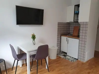 a white table with chairs and a television on a wall at Sweet Vibes Studio at Šiška district, with Parking in Ljubljana