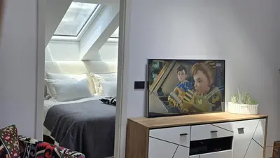 a living room with a tv on a stand next to a bed at Funky Stylish Penthouse in Ljubljana