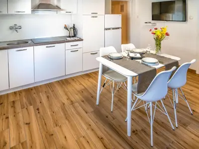 a kitchen with white cabinets and a table and chairs at Apartment Adelsberg Inn-2 by Interhome in Postojna