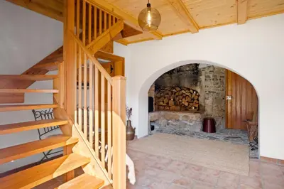 a room with a stone fireplace and wooden stairs at Old Castle Lodge in Kamnik