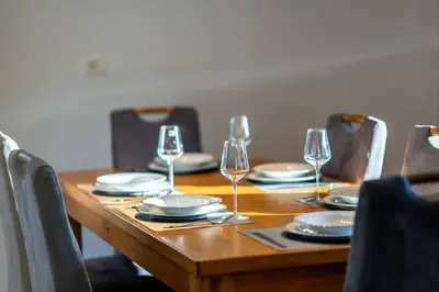 a wooden table with plates and wine glasses on it at Villa Aqua in Moravske Toplice