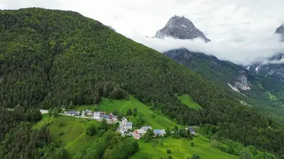 a house on a green hill with a mountain at Apartment Pohar in Log pod Mangartom