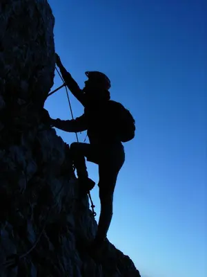 a man is climbing a mountain with a rope at Apartment Pohar in Log pod Mangartom