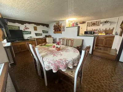 a dining room with a table and chairs and a kitchen at Apartment Pohar in Log pod Mangartom
