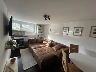 a living room with a brown couch and a table at Betnava Apartment in Maribor