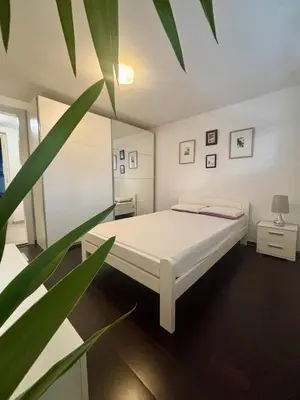 a bedroom with a white bed and a plant at Betnava Apartment in Maribor