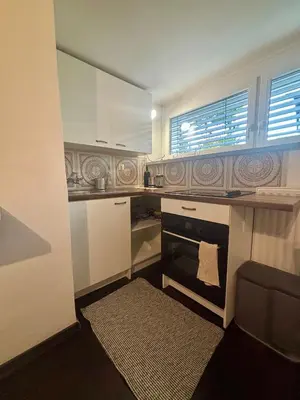 a small kitchen with white cabinets and a window at Betnava Apartment in Maribor