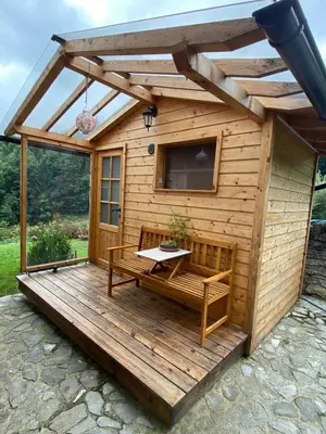a large wooden cabin with a table on a deck at Mountain Escape with Sauna in Kobarid