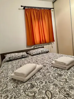 a bed with two pillows on it with an orange curtain at Karol-ina Estate in Branik