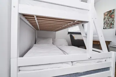 a white bunk bed in a room with a desk at Alpine View Premium in Komenda