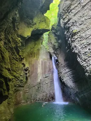 a waterfall in a canyon with a body of water at Caissa - Spacious house in quiet location in Tolmin