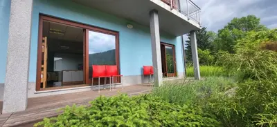 a blue house with red chairs on a deck at Caissa - Spacious house in quiet location in Tolmin