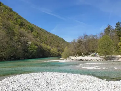 a river with a rocky shore and a mountain at Caissa - Spacious house in quiet location in Tolmin