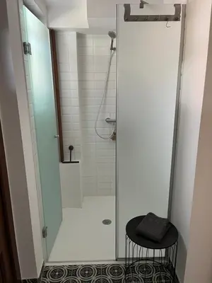 a shower with a glass door and a stool in a bathroom at Apartma Grahor in Selnica ob Dravi