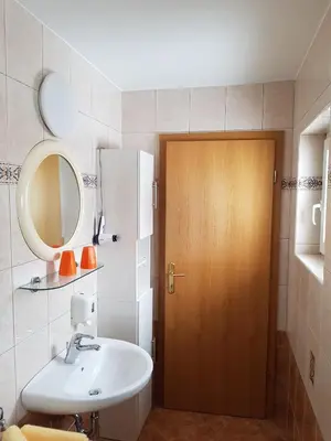 a bathroom with a sink and a wooden door at Penzion Pr' Betel in Jesenice