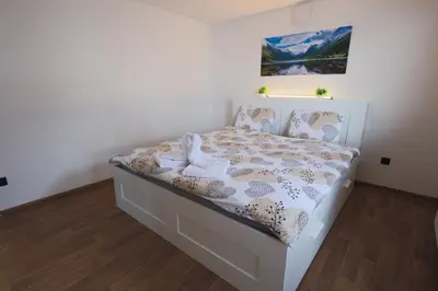 a white bed in a bedroom with a picture on the wall at M&M apartma in Bohinj