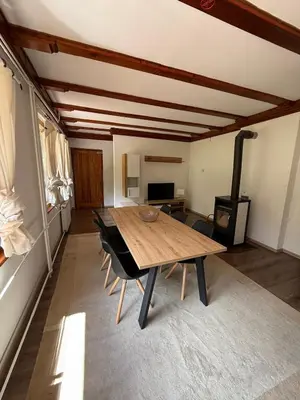 a dining room with a wooden table and a stove at Cozy Mountain Stay near Kranjska Gora in Gozd Martuljek