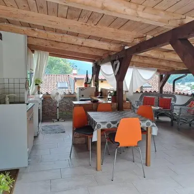 a patio with a table and chairs under a wooden roof at Hiša Gadiča in Tolmin