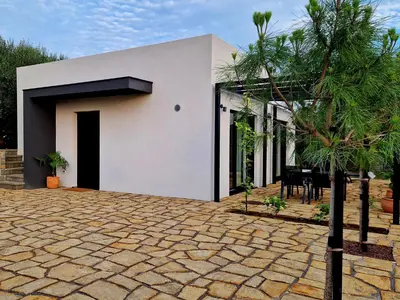 a white house with a black door and a patio at House B in Dekani