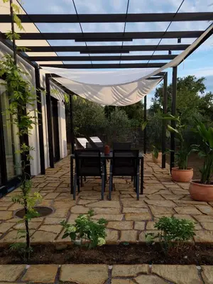 a patio with a table and chairs under a pergola at House B in Dekani