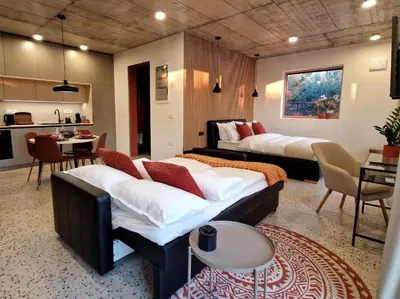 two beds in a room with a kitchen and a table at House B in Dekani