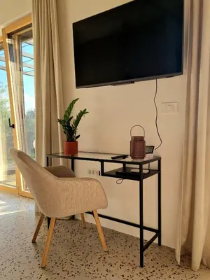 a chair and a desk with a television on a wall at House B in Dekani