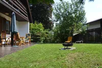a backyard with a grill and chairs and an umbrella at Holiday House Bohinj in Bohinj