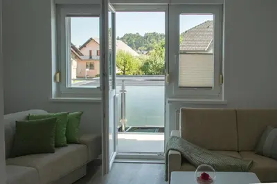a living room with a couch and two windows at Apartma LONČAR in Horjul